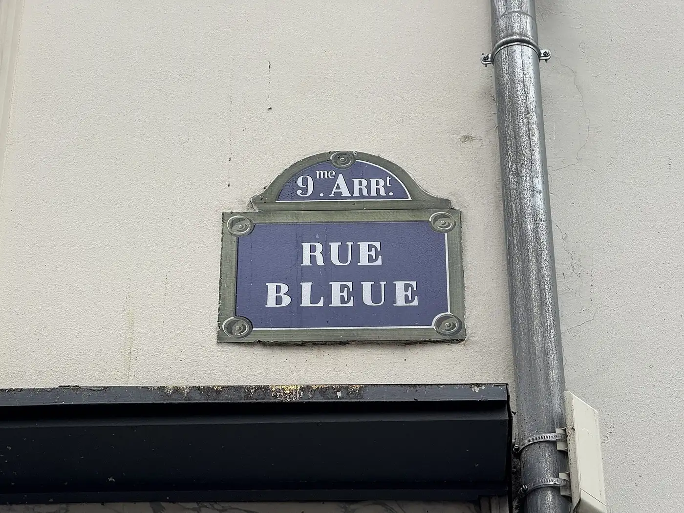 Une plaque de rue parisienne, qui porte le numéro d'arrondissement au-dessus du nom