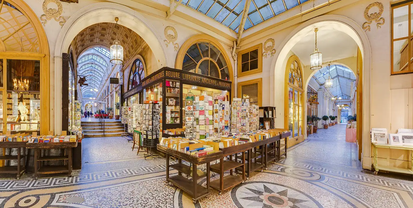 La galerie Vivienne, son sol en mosaïque, sa verrière et une librairie ancienne au croisement de deux branches de la galerie