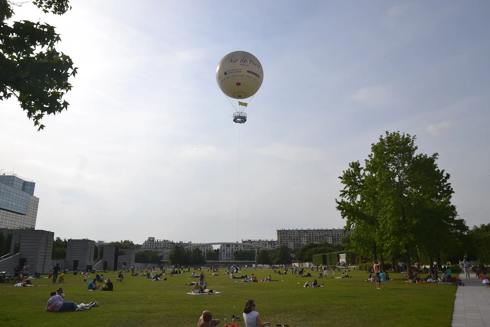 La grande pelouse du parc André-Citroën, avec le ballon captif en l'air et des gens assis dans l'herbe
