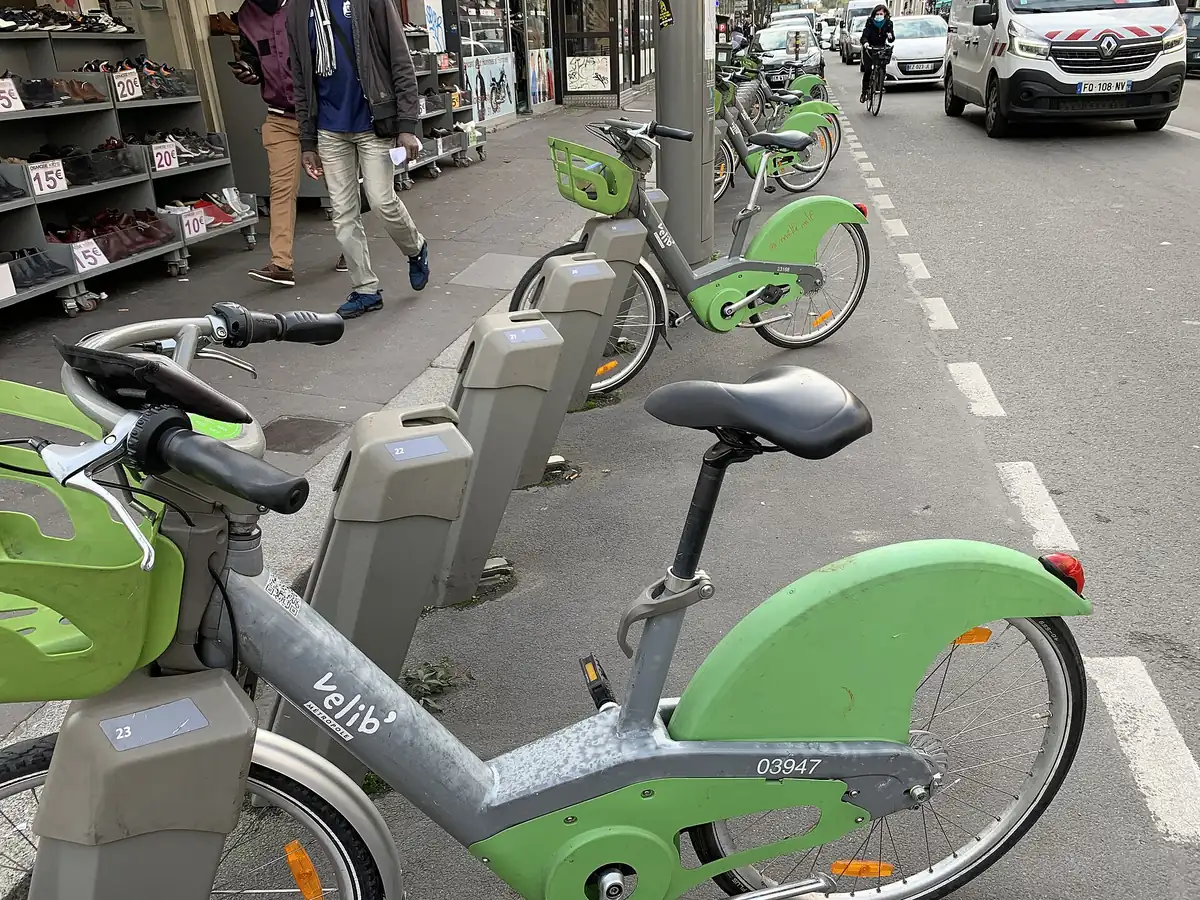 Une station Vélib' avec des vélos verts mécaniques et des vélos bleus électriques accrochés aux bornes